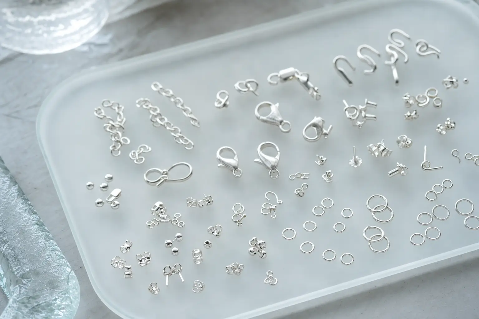 Organized sterling silver links and findings in a cool gray tray