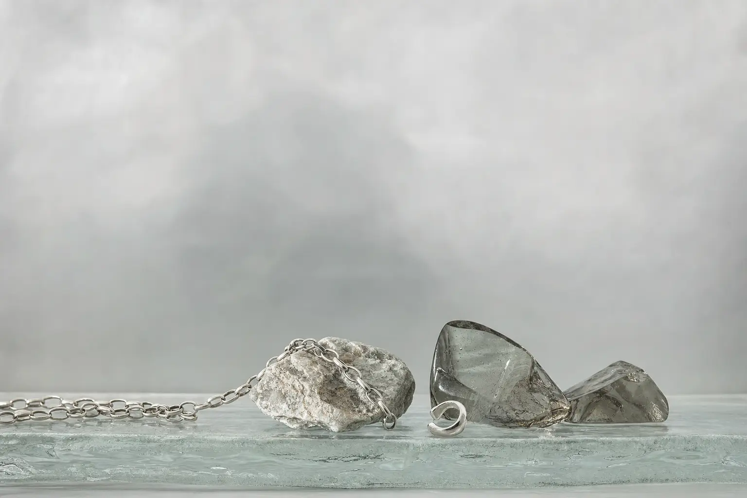 Wide cool gray horizon still life with silver chain and smoky glass