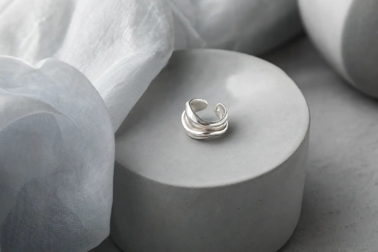 Fluid sculptural silver wave cuff on cool gray ceramic