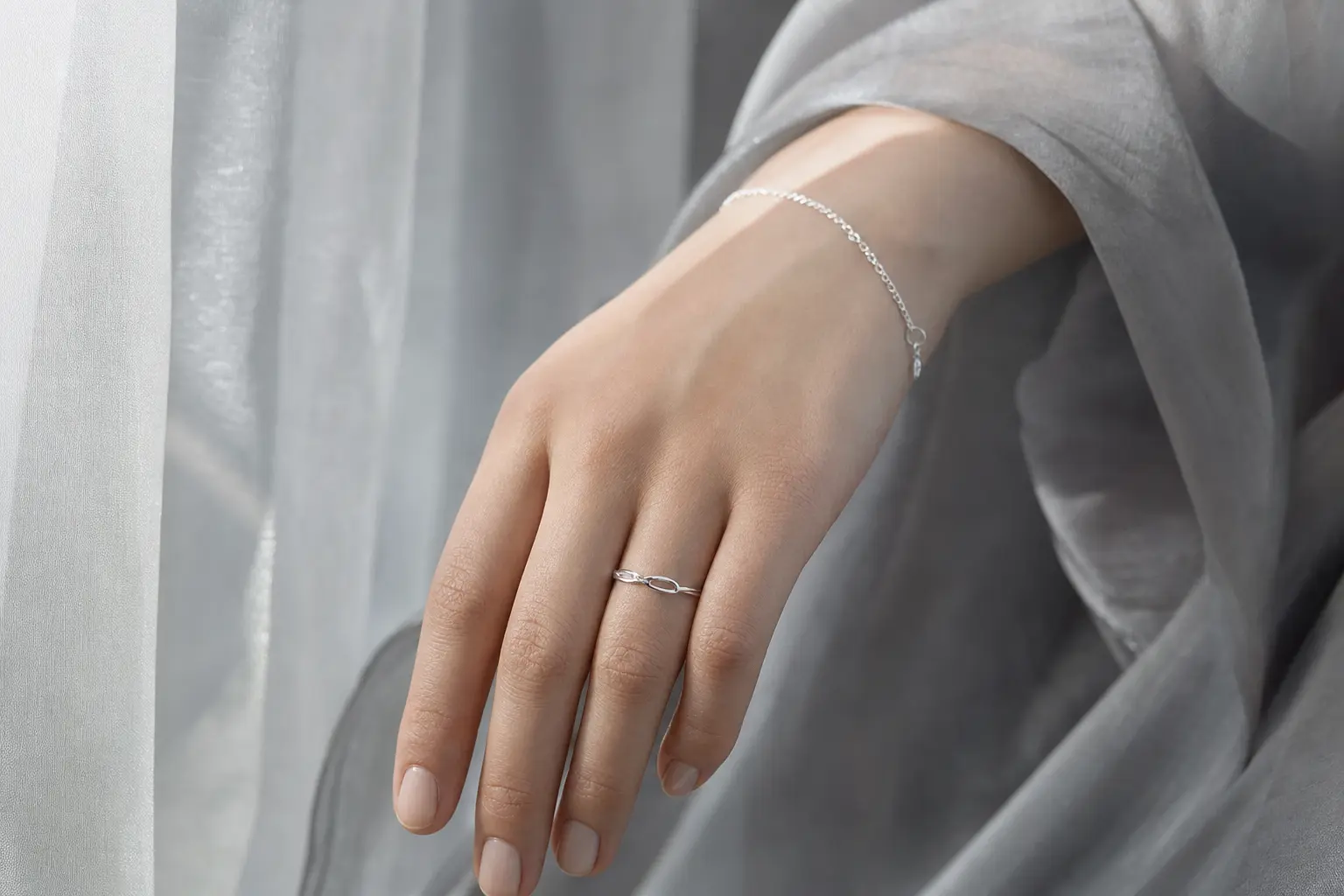 Natural hand wearing a silver ring and bracelet in cool gray light