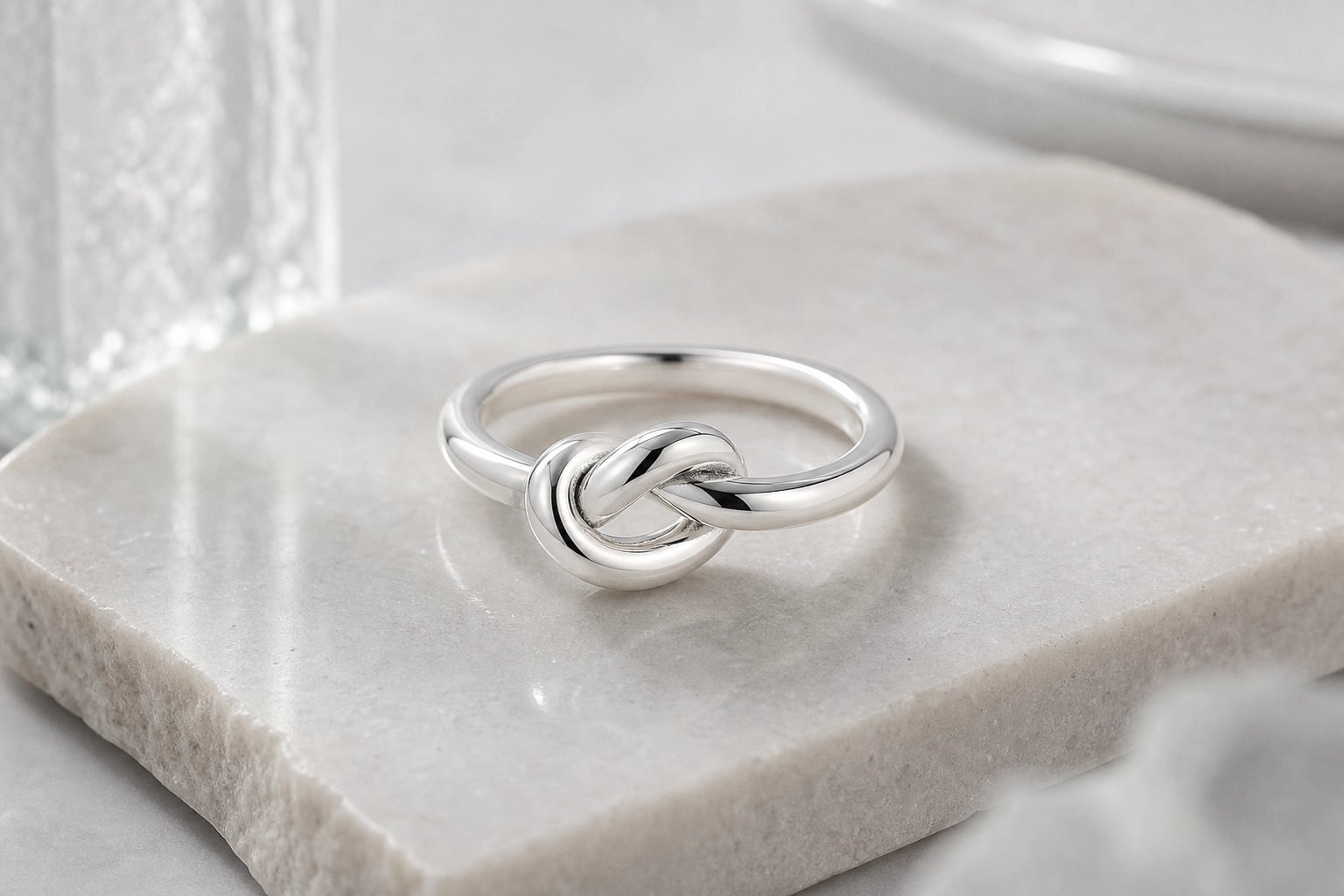 Polished silver knot ring resting on a pale marble slab