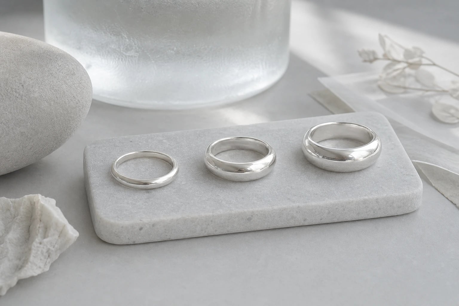 Three plain domed silver band rings in graded widths on a marble tray