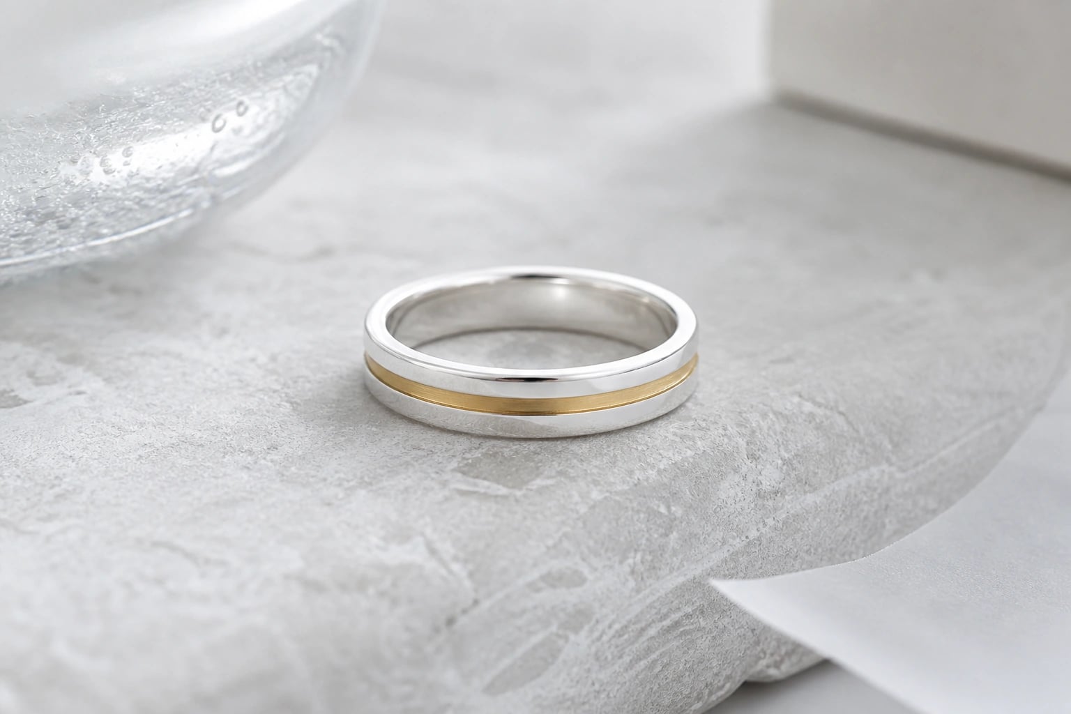 Silver band ring with a recessed champagne-brass inlay stripe on pale stone